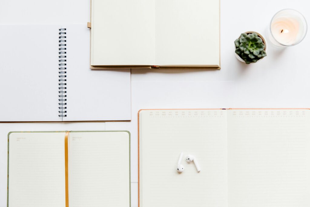A clean flat lay of notebooks, planners, Airpods, and succulents, ideal for productivity themes.
