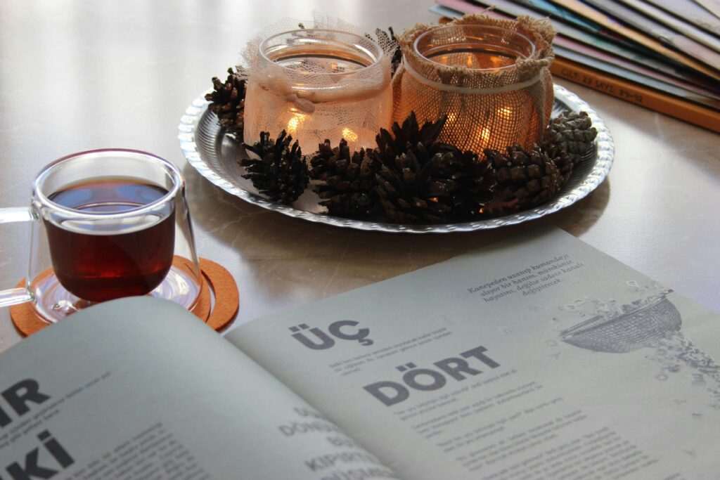 Warm candlelit setting featuring a book, tea, and decorative candles with pinecones.