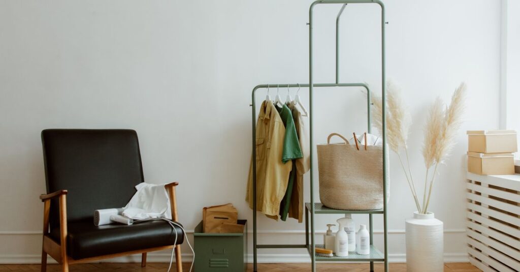 A modern home corner with a leather armchair, clothing rack, and decorative elements.