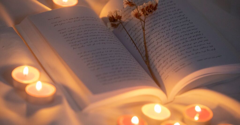 Open book surrounded by candles and dried flowers creating a warm, inviting atmosphere.