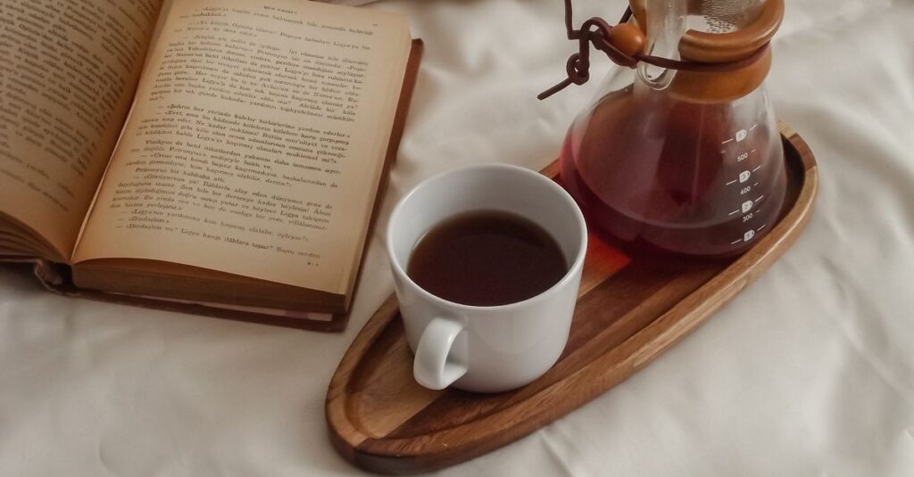 Enjoy a tranquil morning with a fresh cup of coffee and an open book on a bed, creating a warm and inviting atmosphere.