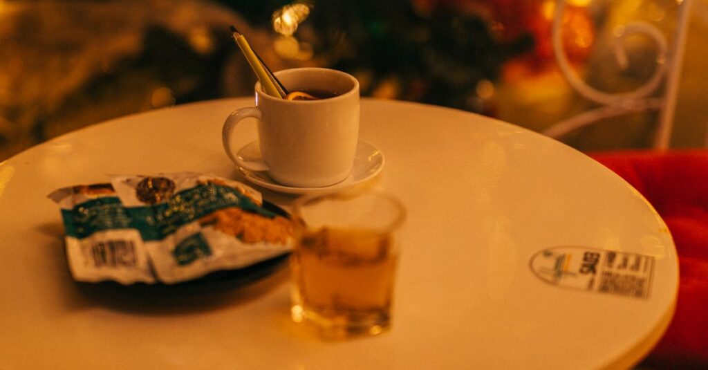 A warm drink and biscuit on a cozy table with holiday decorations.