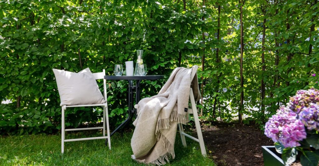A tranquil backyard scene with chairs, table, and lush greenery, perfect for relaxation.