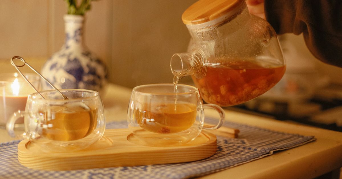 Warm indoor setting with tea being poured and candlelight for a cozy atmosphere.