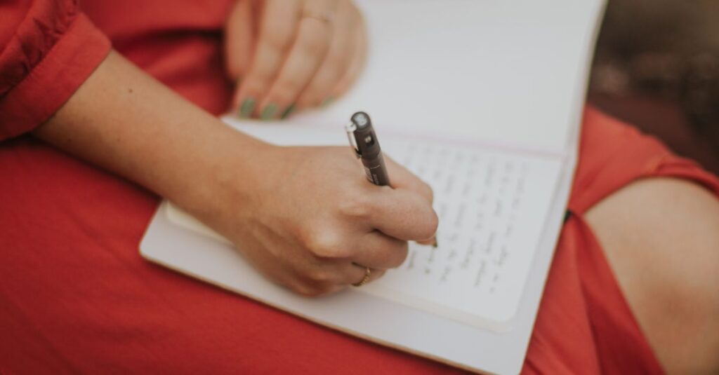 Close-up of a woman writing in a journal outdoors, capturing a serene moment in nature.