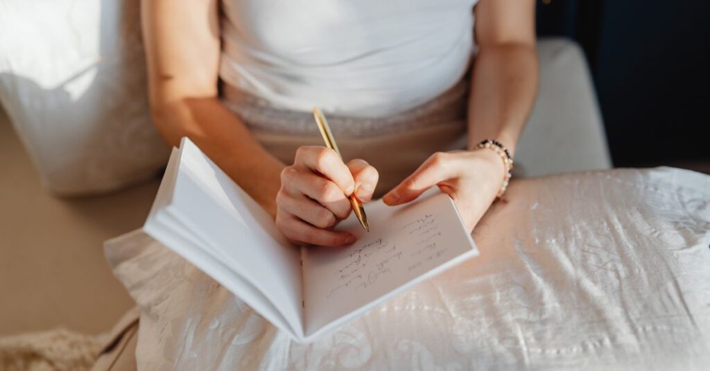 Close-up of a woman writing in a journal while sitting comfortably indoors.