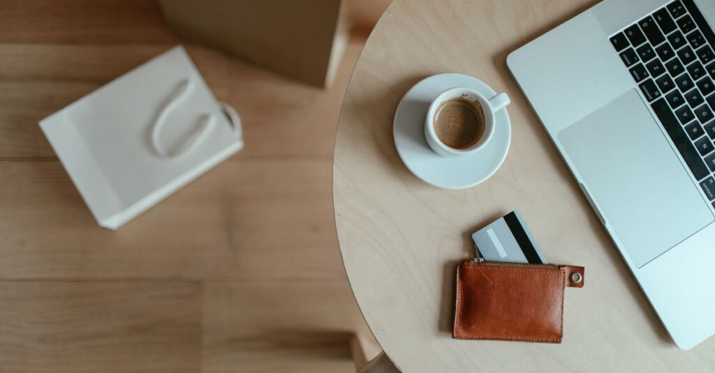 Minimalist top view of a workspace with coffee, laptop, and wallet on a wooden table.
