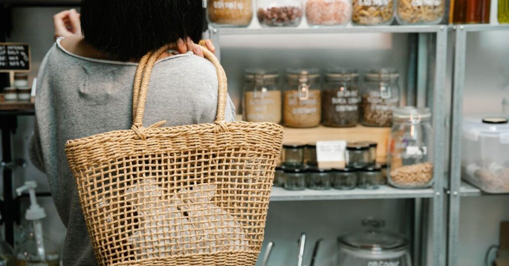 Back view of crop anonymous female with short dark hair choosing goods on shelves in shop