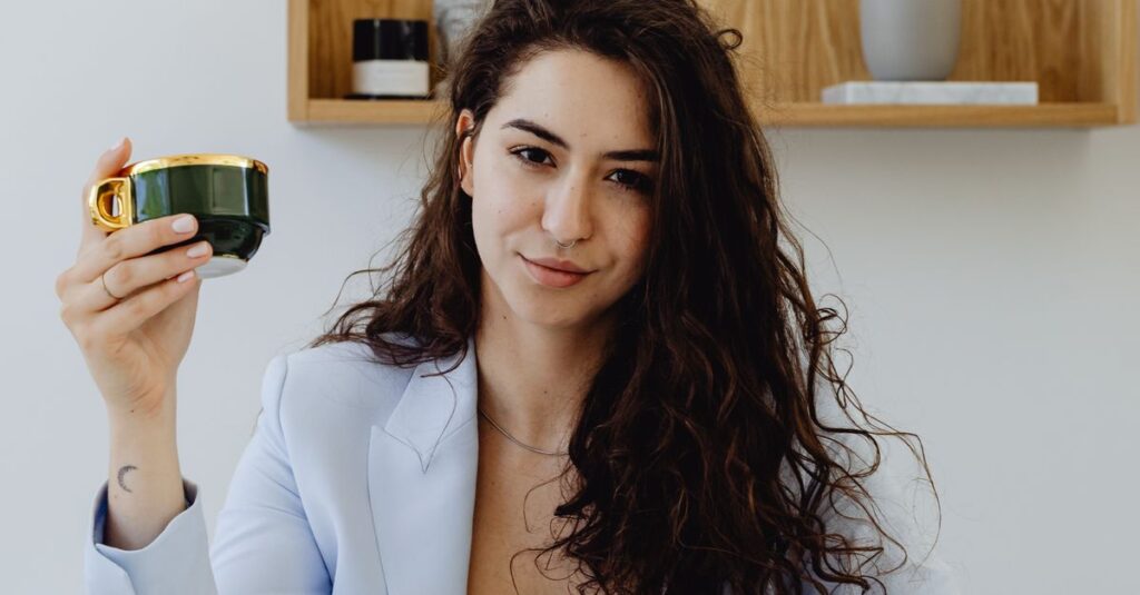Professional woman in business attire holding a coffee cup in a modern office setting.
