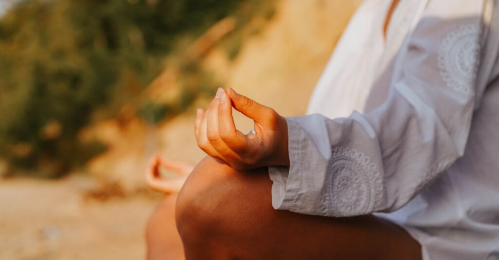 A close-up of a person meditating outdoors, capturing mindfulness at sunset on a beach.