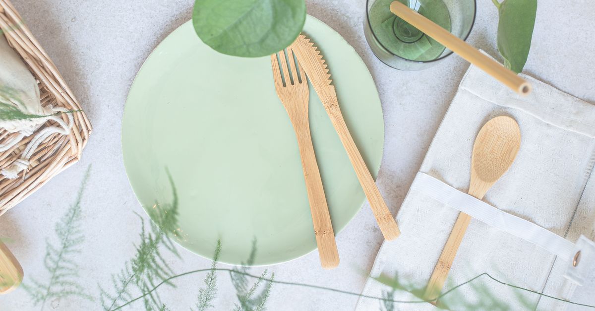 Top view of a green ceramic plate with bamboo utensils and eco-friendly dining accessories.
